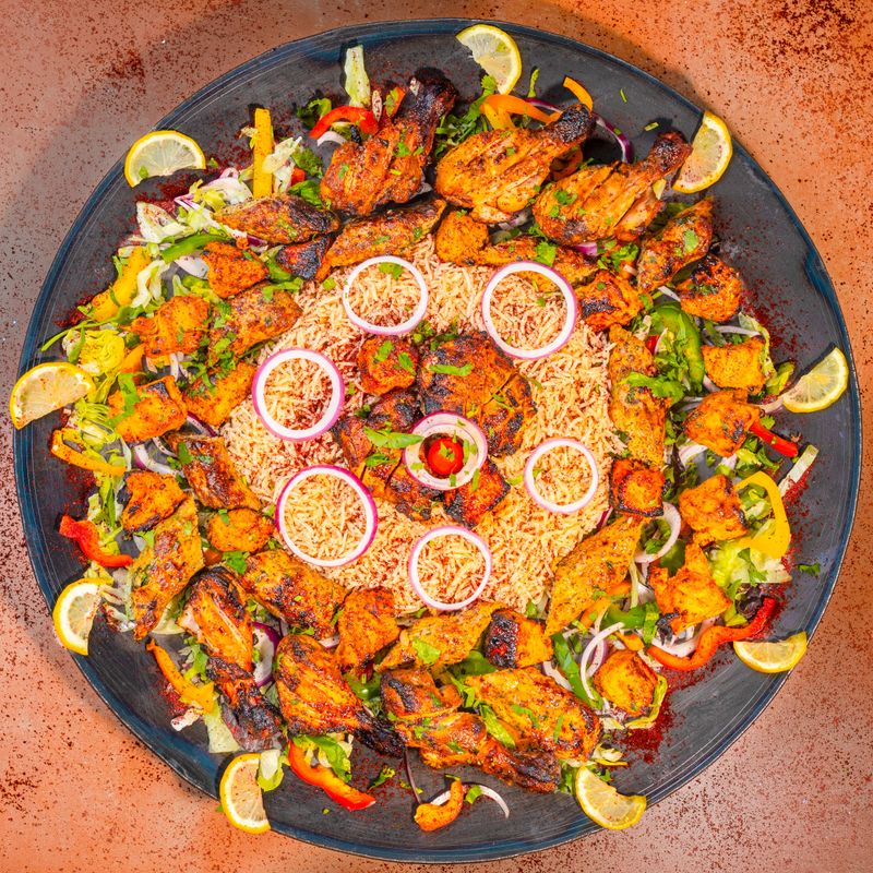 A platter of grilled chicken and rice, seen from above.